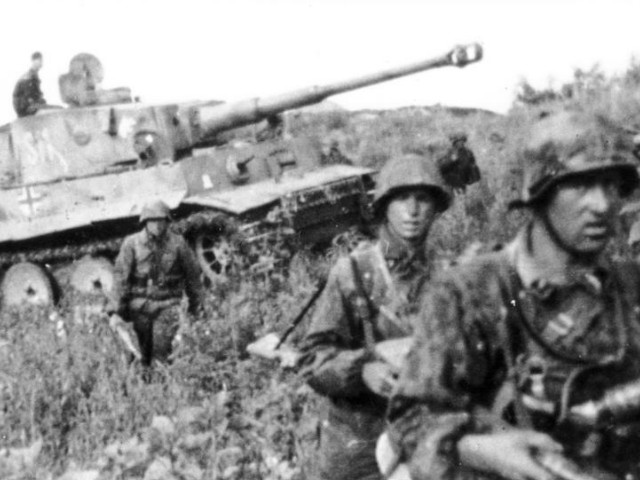 The heat of battle. A 2nd SS Division “Das Reich” Tiger I supported by grizzled Panzergrenadiers